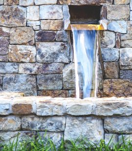 Close-up view of artistic water fountain with vibrant stone wall, shallow DOF