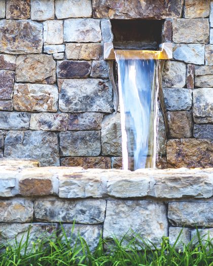 Close-up view of artistic water fountain with vibrant stone wall, shallow DOF